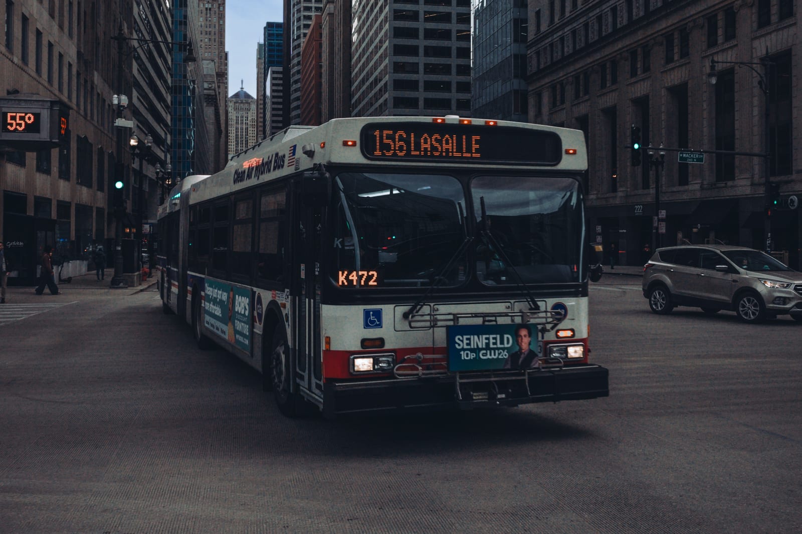 An articulated Chicago Transit Authority bus showing route 156 LaSalle crosses an intersection among downtown Chicago office towers.