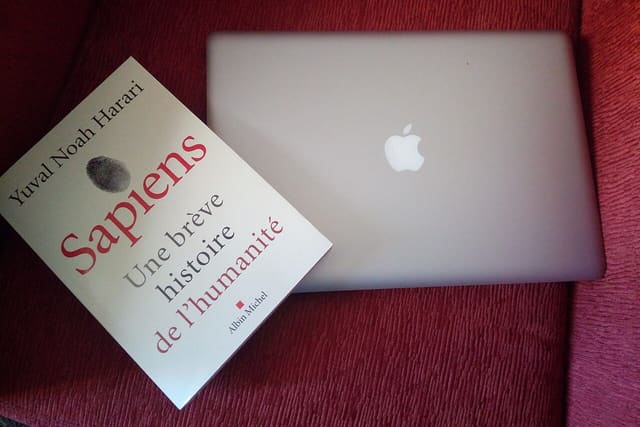A closed laptop and a book on a chair