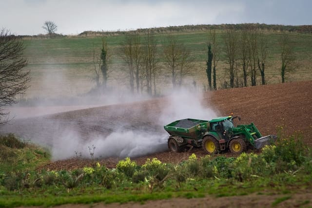 A tractor spreading lime across a field
