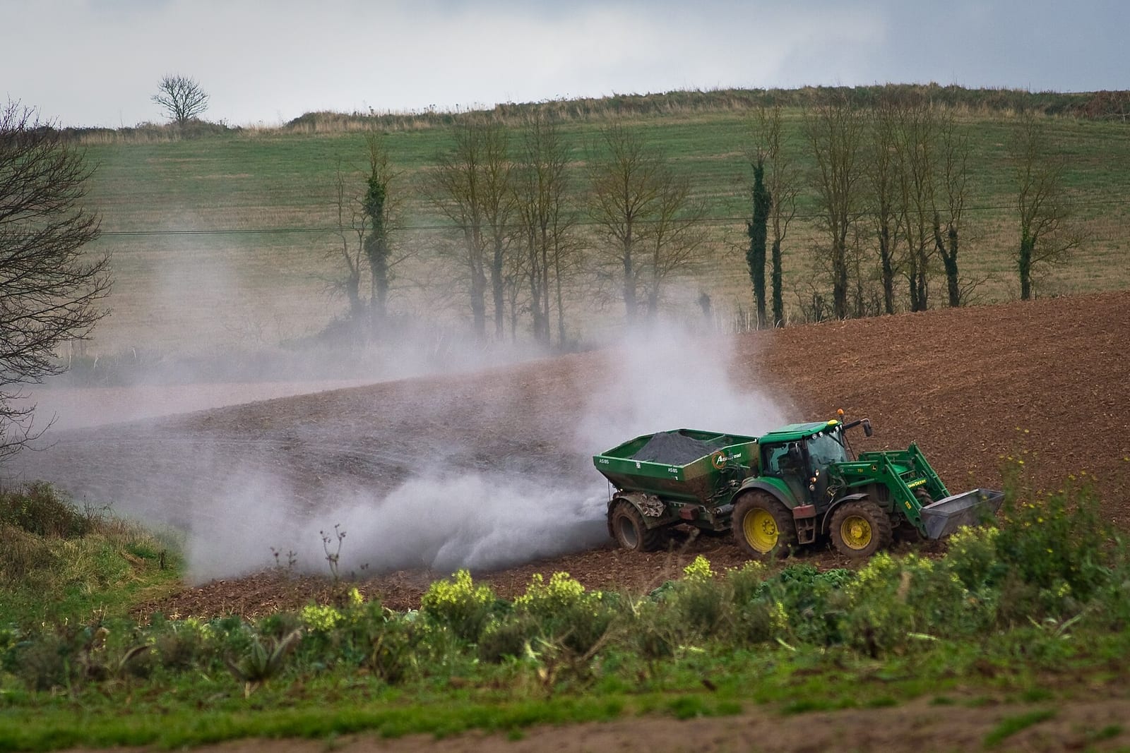 A tractor spreading lime across a field