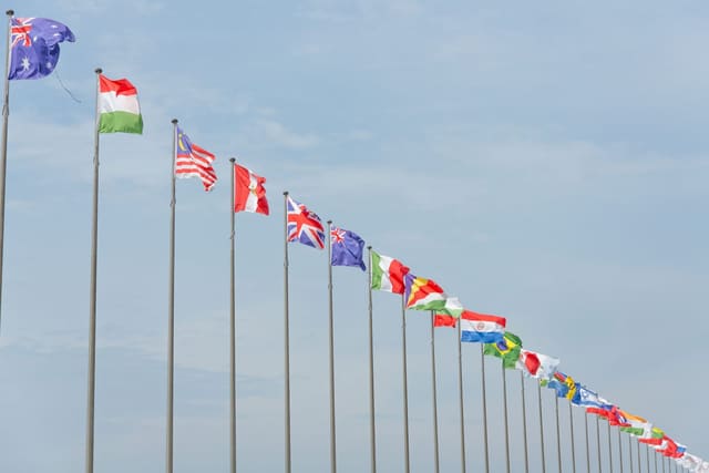 A row of national flags on tall poles against the sky