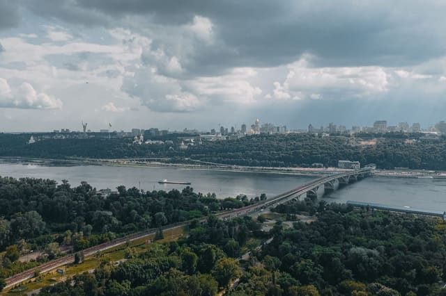 Aerial view of Kyiv across the Dnipro River, with the Metro Bridge, the Pechersk Lavra's golden domes and the Motherland Monument on the far bank
