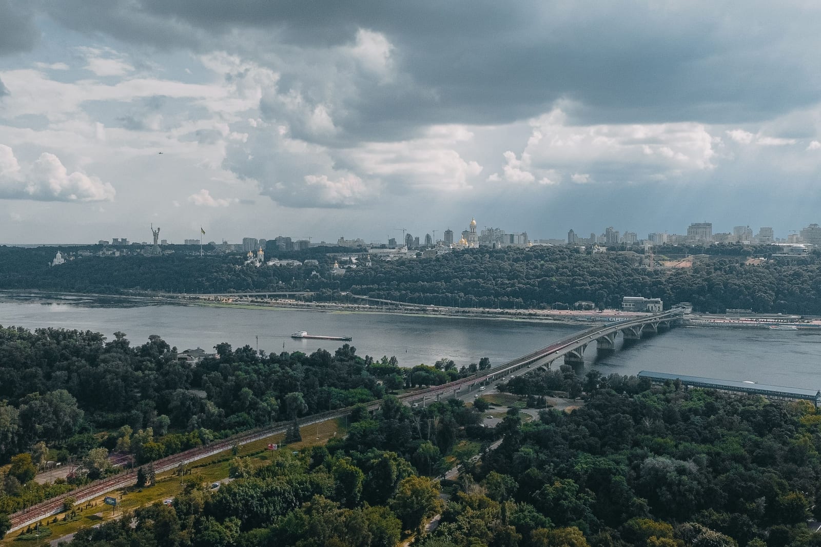 Aerial view of Kyiv across the Dnipro River, with the Metro Bridge, the Pechersk Lavra's golden domes and the Motherland Monument on the far bank