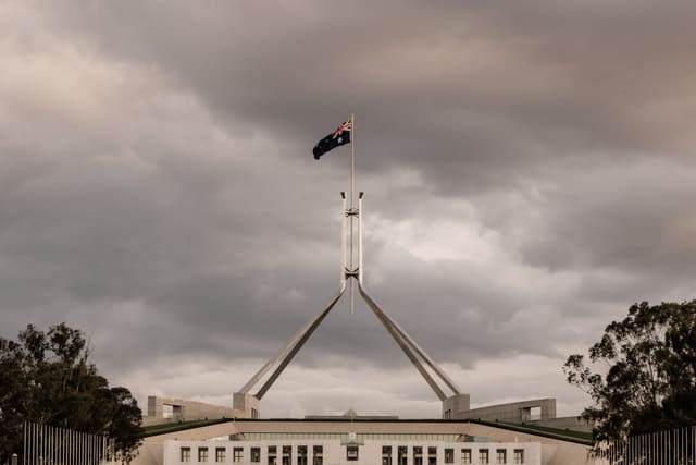 The flagpole above Parliament House in Canberra under a cloudy sky