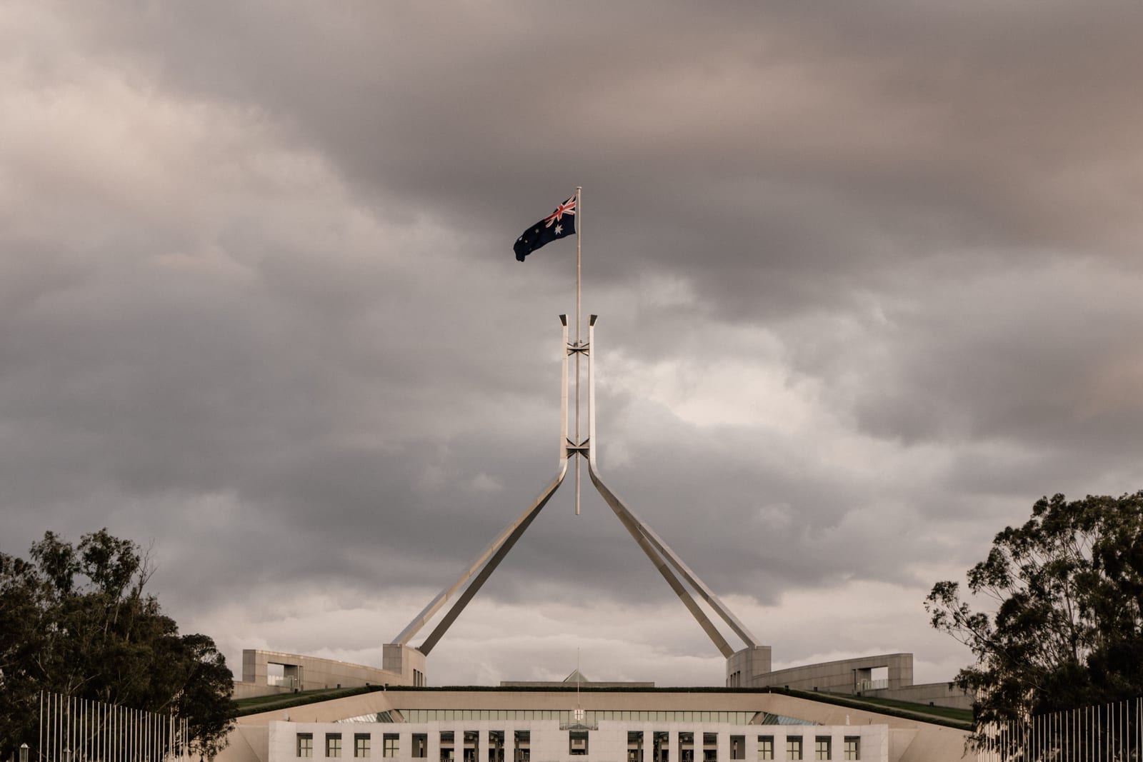 The flagpole above Parliament House in Canberra under a cloudy sky