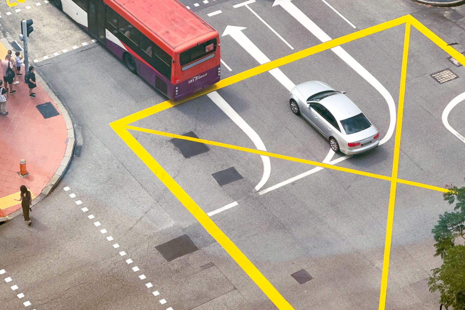 A red bus and cars at a city junction seen from above
