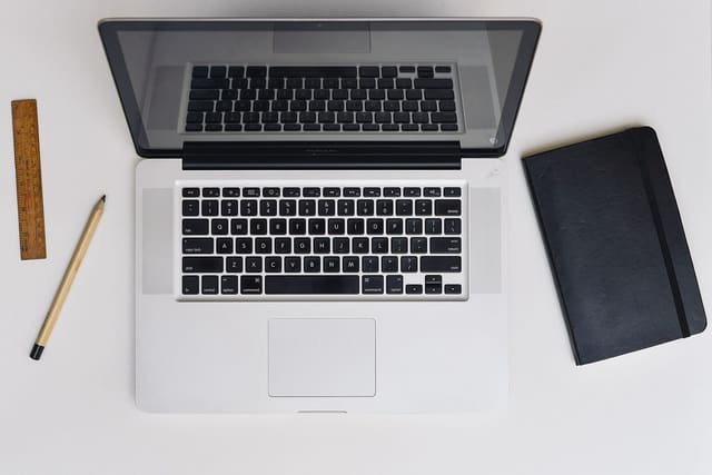 A laptop, notebook and pencil on a desk