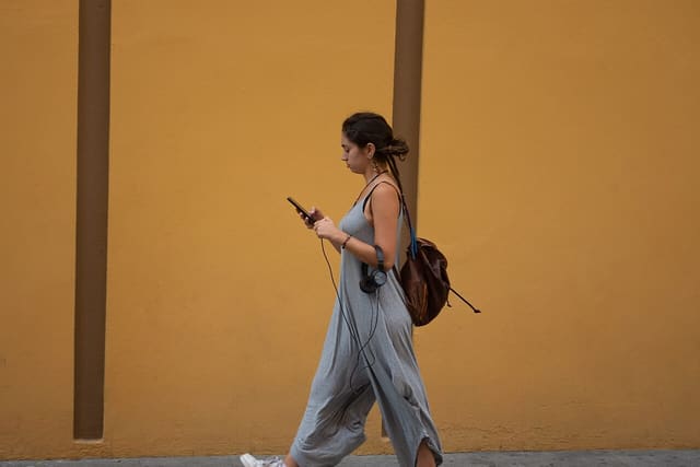A young woman walking while looking at her phone