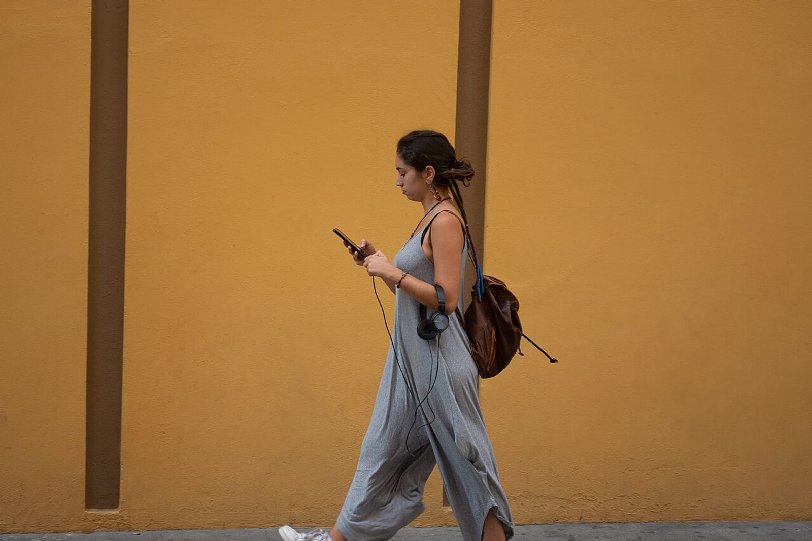 A young woman walking while looking at her phone